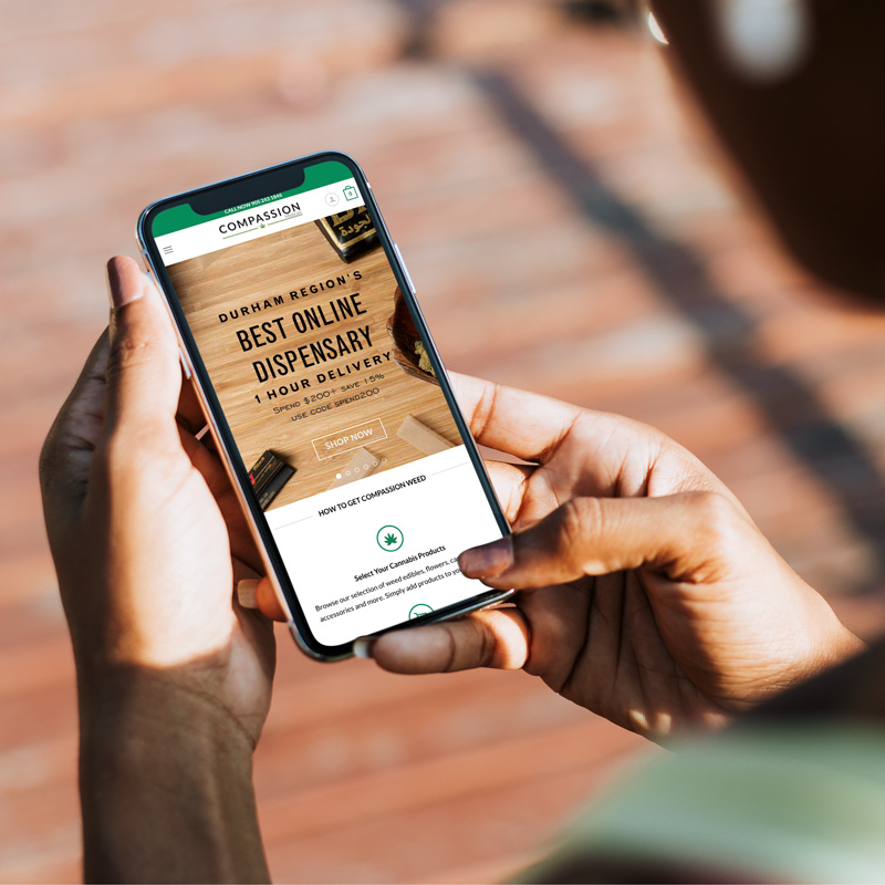 a woman holds a mobile phone displaying the compassion medicals website