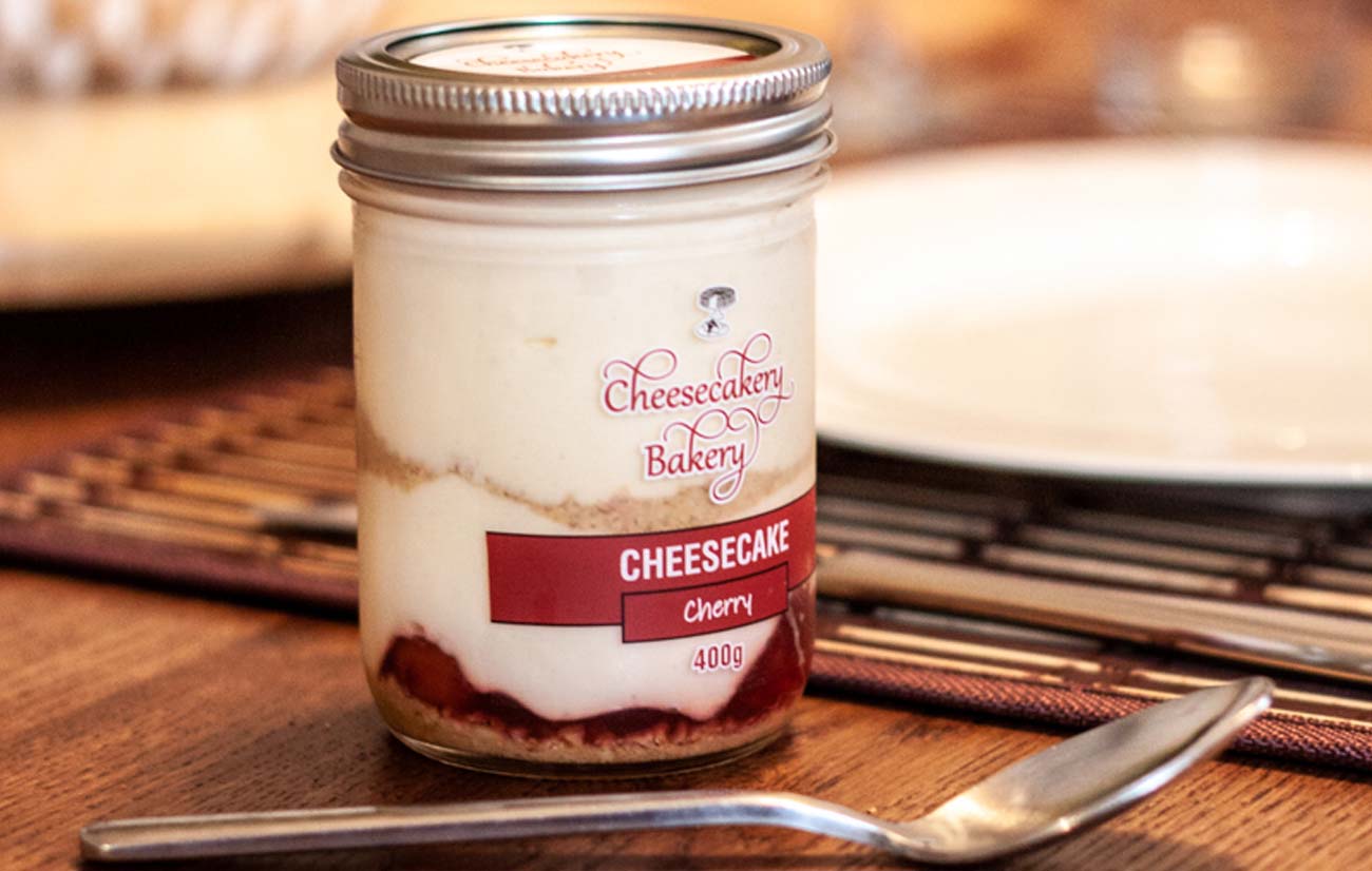a mason jar of cheesecake sits on a dinner table
