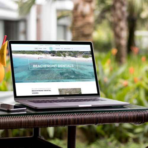 a laptop sits outside displaying the barbuda cottages website