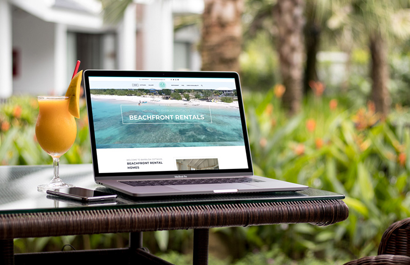 a laptop sits outside displaying the barbuda cottages website